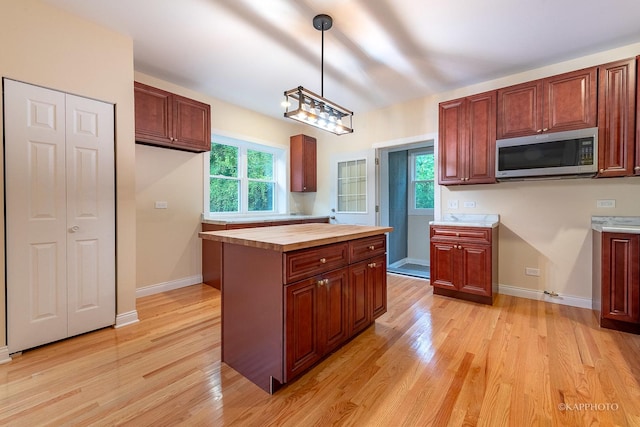 kitchen with plenty of natural light, butcher block counters, pendant lighting, and light hardwood / wood-style floors