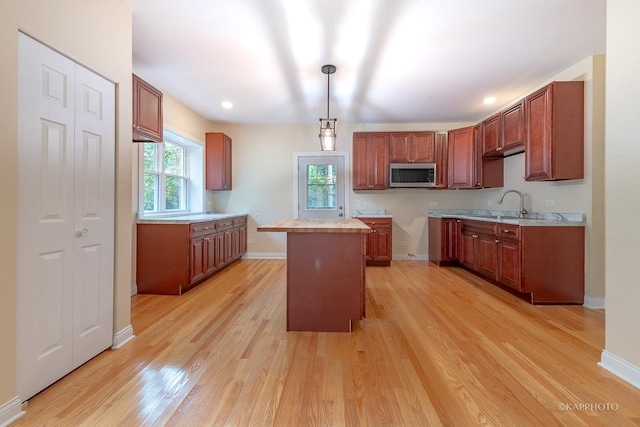 kitchen with a kitchen island, sink, light hardwood / wood-style floors, and decorative light fixtures