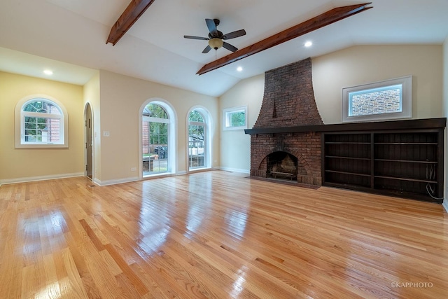 unfurnished living room with a brick fireplace, lofted ceiling with beams, light hardwood / wood-style floors, and ceiling fan