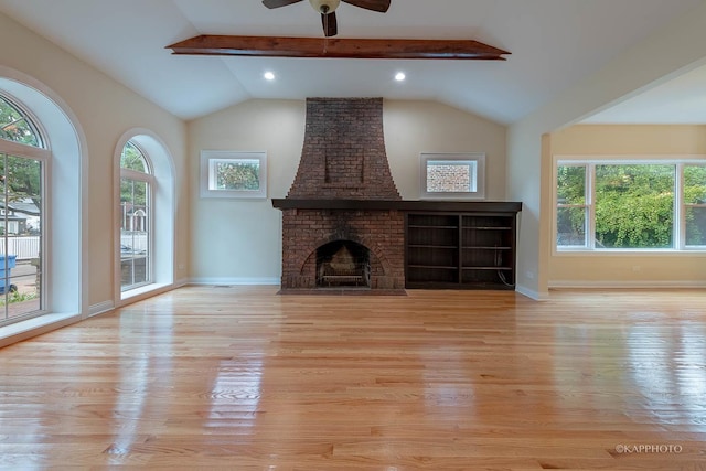 unfurnished living room featuring light hardwood / wood-style flooring, vaulted ceiling with beams, a fireplace, and ceiling fan