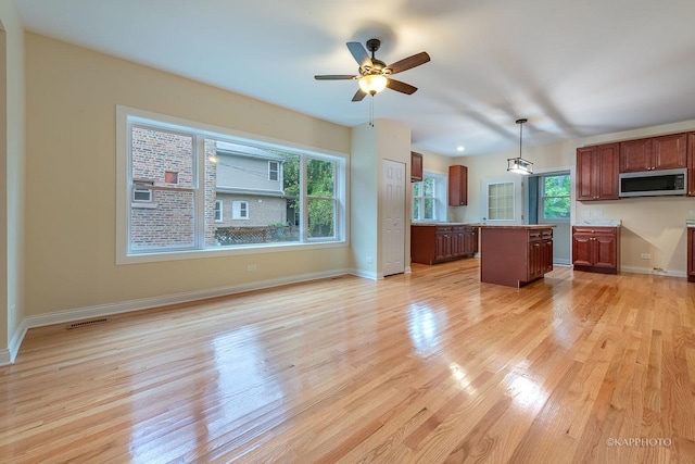 kitchen featuring plenty of natural light, decorative light fixtures, a center island, and light hardwood / wood-style flooring