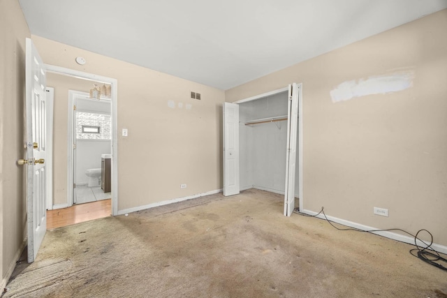 unfurnished bedroom with light colored carpet and a closet