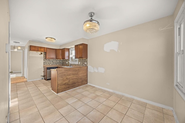 kitchen with kitchen peninsula, stainless steel dishwasher, sink, tasteful backsplash, and light tile patterned floors