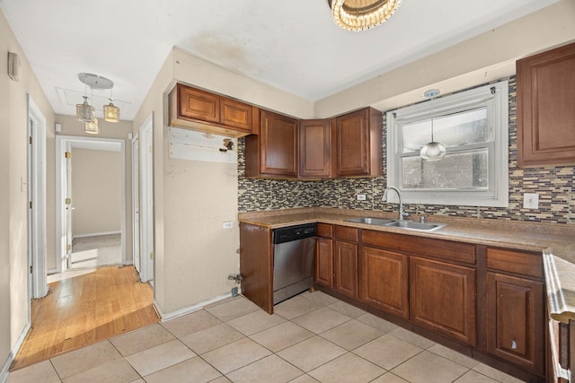 kitchen featuring light tile patterned floors, decorative backsplash, stainless steel dishwasher, sink, and decorative light fixtures