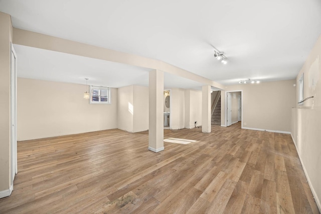 basement featuring rail lighting and light wood-type flooring