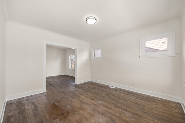 unfurnished room with ornamental molding and dark wood-type flooring