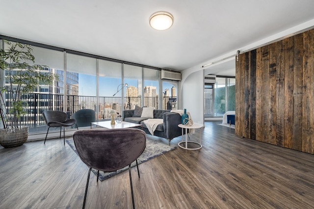 living room with a baseboard radiator, hardwood / wood-style floors, a wall of windows, and a wall mounted AC