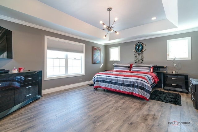 bedroom featuring a raised ceiling, an inviting chandelier, hardwood / wood-style floors, and ornamental molding