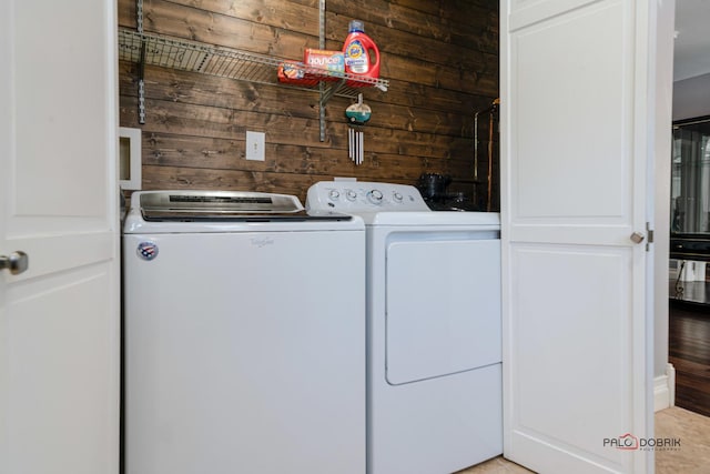 laundry room with washing machine and dryer and wooden walls