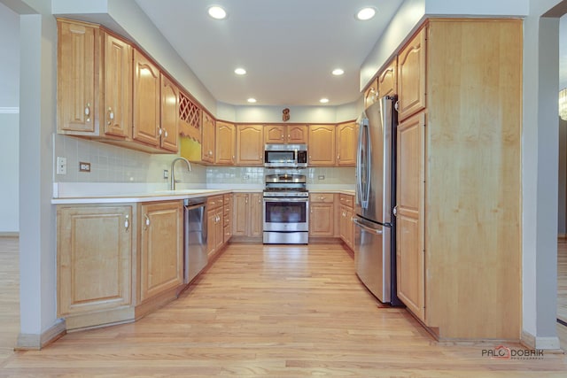 kitchen featuring sink, backsplash, stainless steel appliances, and light hardwood / wood-style floors