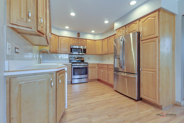 kitchen featuring sink, backsplash, stainless steel appliances, light brown cabinetry, and light wood-type flooring