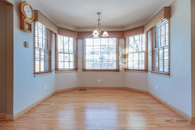 empty room featuring an inviting chandelier and light wood-type flooring