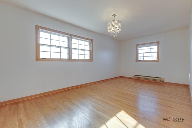 unfurnished room featuring baseboard heating, light hardwood / wood-style flooring, and a notable chandelier