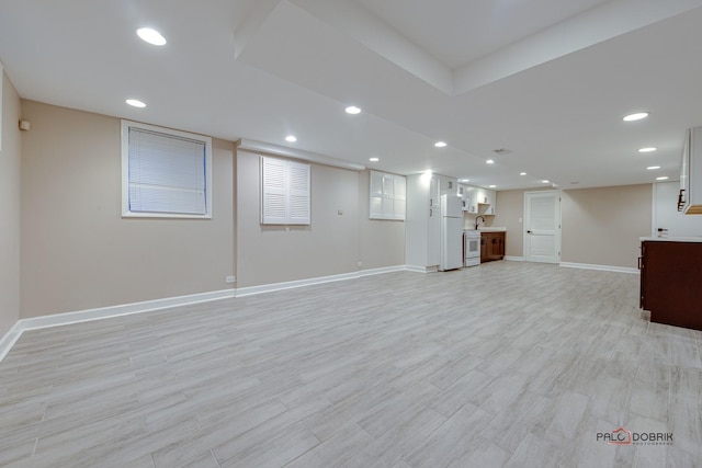 basement with white refrigerator and light hardwood / wood-style floors