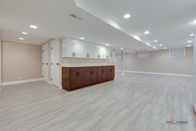 kitchen with white cabinetry, dark brown cabinets, and light hardwood / wood-style flooring