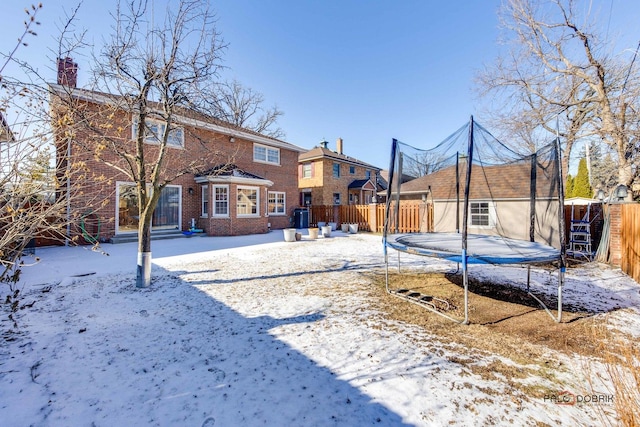 snow covered house featuring central AC unit and a trampoline