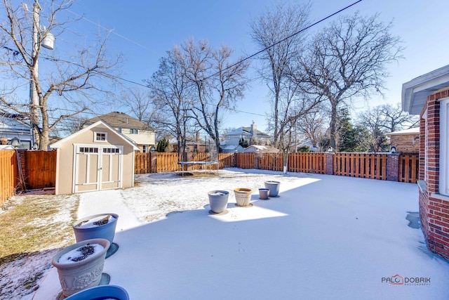 snowy yard with a trampoline and a storage shed