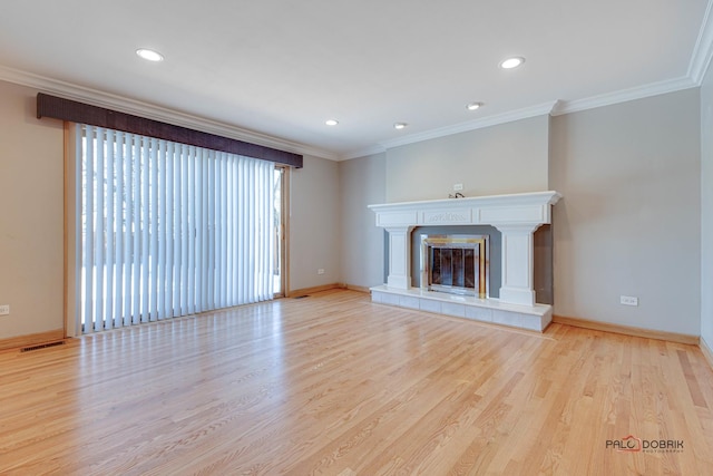 unfurnished living room featuring a tiled fireplace, ornamental molding, and light wood-type flooring