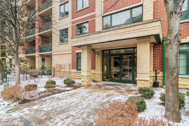 snow covered property entrance featuring french doors