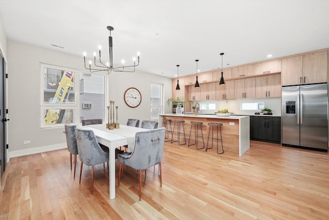 dining area featuring sink, light wood-type flooring, and a notable chandelier