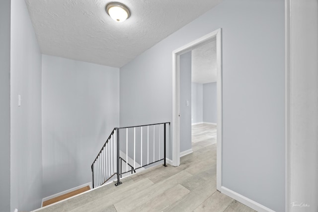 corridor featuring light hardwood / wood-style flooring and a textured ceiling