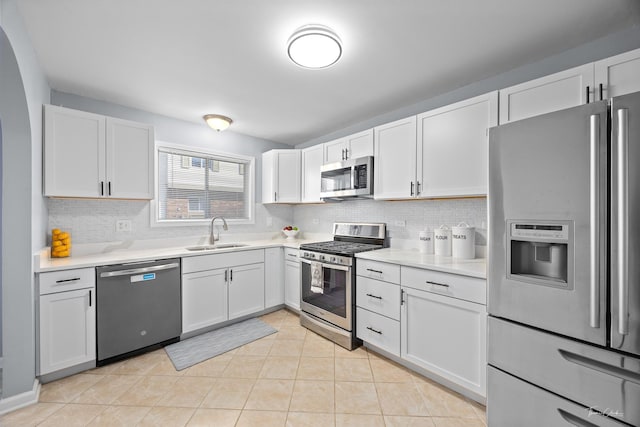 kitchen with sink, tasteful backsplash, light tile patterned floors, appliances with stainless steel finishes, and white cabinets