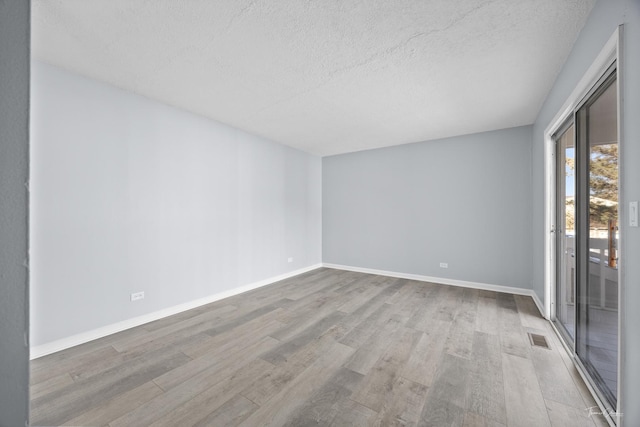 unfurnished room with light hardwood / wood-style floors and a textured ceiling