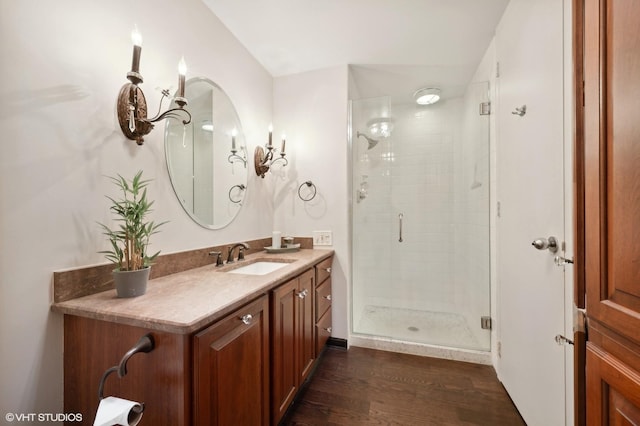 bathroom with wood-type flooring, a shower with door, and vanity