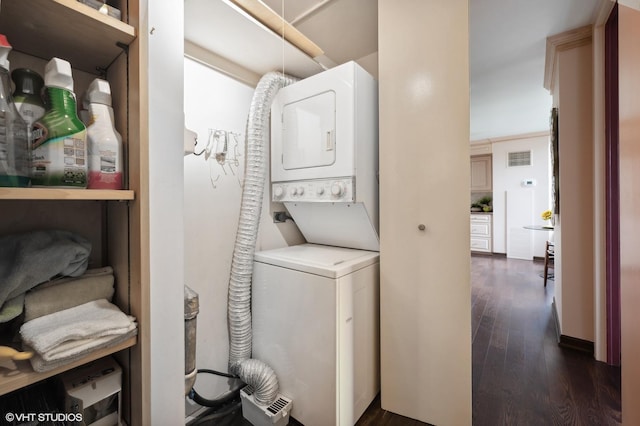 washroom with crown molding, dark hardwood / wood-style floors, and stacked washer and dryer