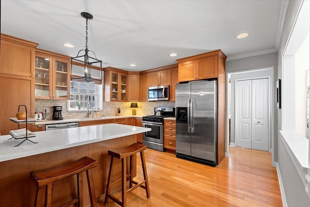 kitchen featuring sink, a breakfast bar area, hanging light fixtures, appliances with stainless steel finishes, and decorative backsplash