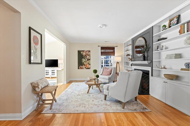 living area featuring crown molding, light hardwood / wood-style floors, and built in features