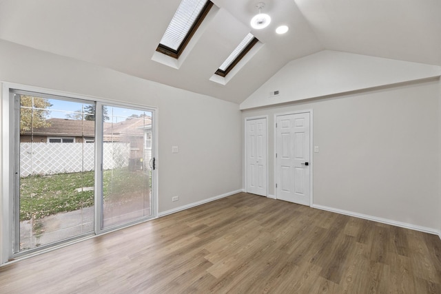 unfurnished room featuring hardwood / wood-style floors and lofted ceiling with skylight