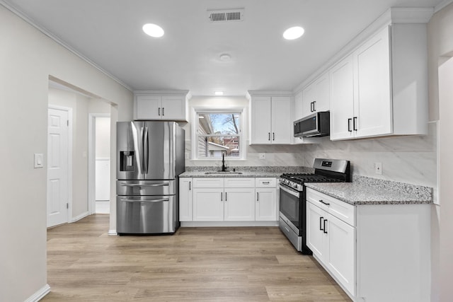 kitchen with light stone countertops, sink, white cabinetry, and stainless steel appliances