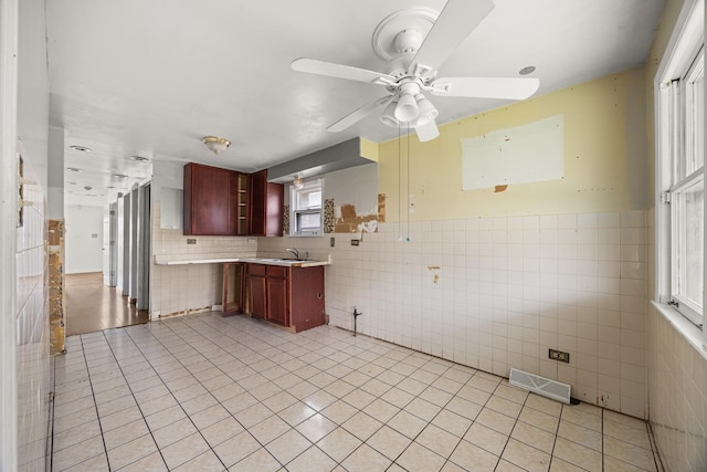 kitchen featuring tile walls, light tile patterned floors, sink, kitchen peninsula, and ceiling fan