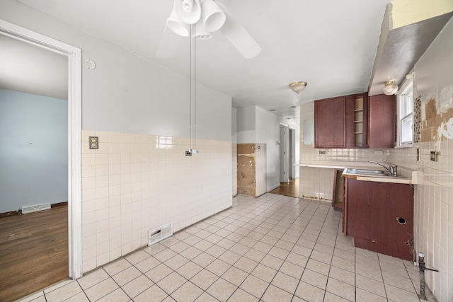 kitchen with ceiling fan, sink, tile walls, and light tile patterned floors