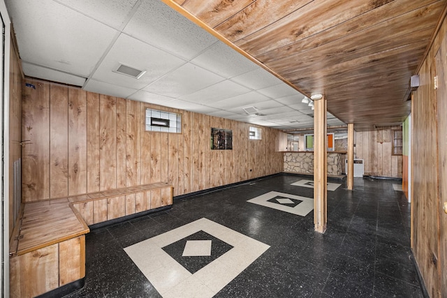 basement with wood walls and a drop ceiling