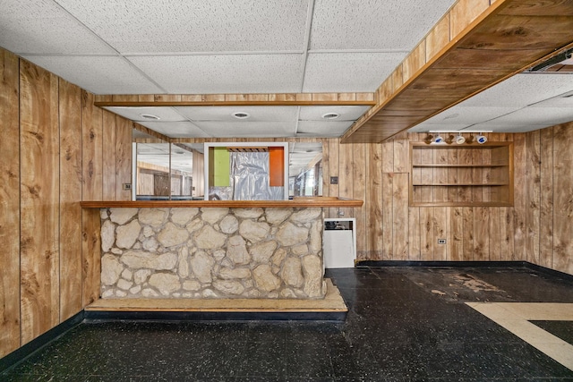 bar featuring wood walls and a drop ceiling