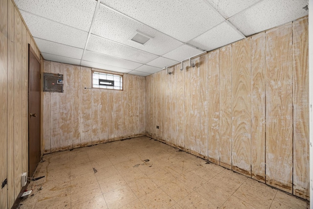 basement with a paneled ceiling and wooden walls