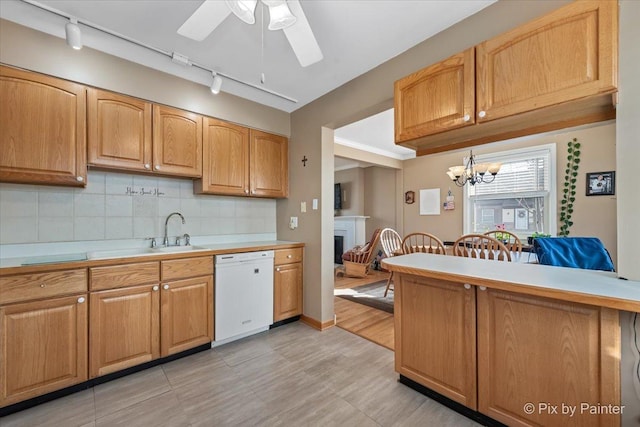 kitchen with dishwasher, sink, ceiling fan with notable chandelier, and decorative backsplash