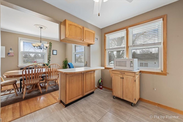 kitchen featuring pendant lighting, crown molding, light brown cabinetry, ceiling fan with notable chandelier, and kitchen peninsula