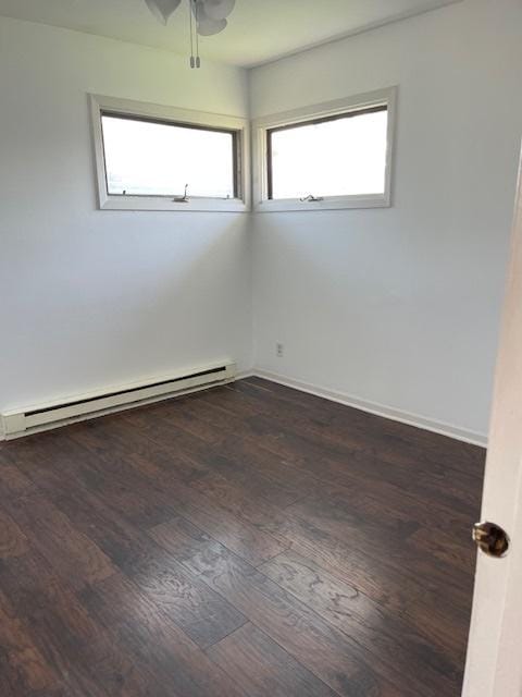 empty room with ceiling fan, a baseboard heating unit, and dark hardwood / wood-style flooring