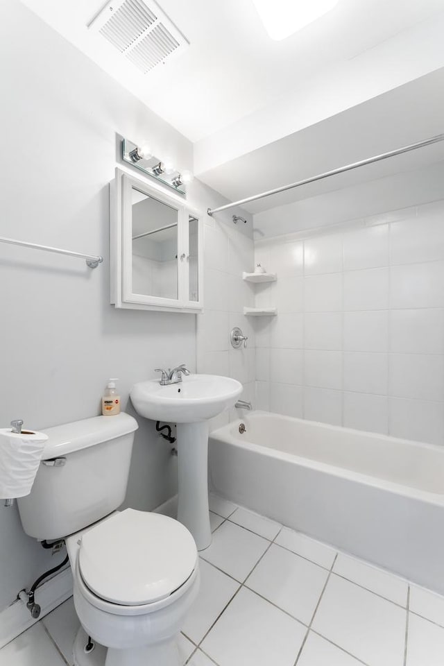 bathroom with toilet, tiled shower / bath combo, and tile patterned flooring