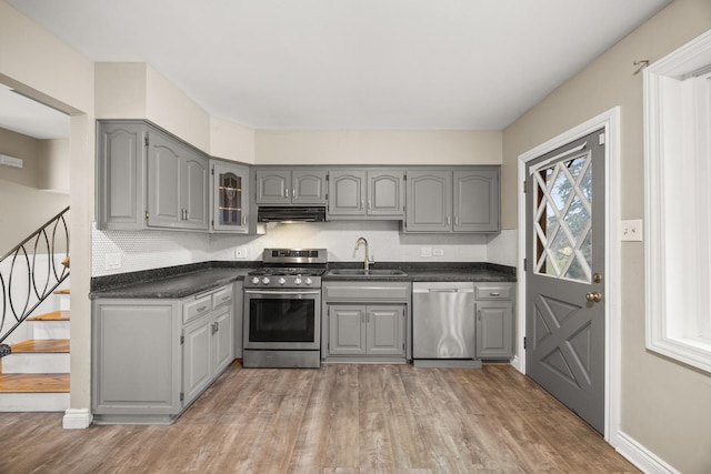 kitchen with sink, wood-type flooring, appliances with stainless steel finishes, and gray cabinetry