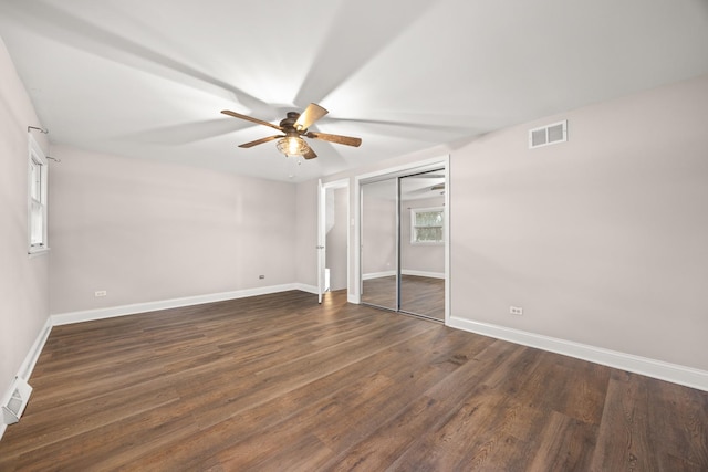 unfurnished bedroom with ceiling fan and dark wood-type flooring