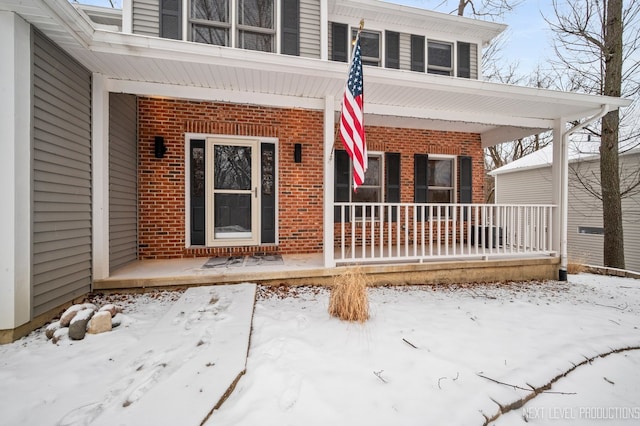 snow covered property entrance with covered porch