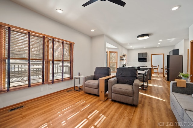 living room with ceiling fan and light hardwood / wood-style floors