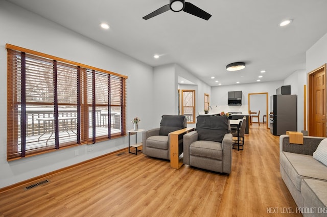 living room with light hardwood / wood-style flooring and ceiling fan