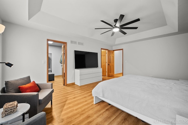 bedroom with a tray ceiling, ceiling fan, and hardwood / wood-style flooring