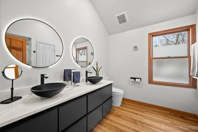 bathroom featuring hardwood / wood-style flooring, lofted ceiling, toilet, and vanity