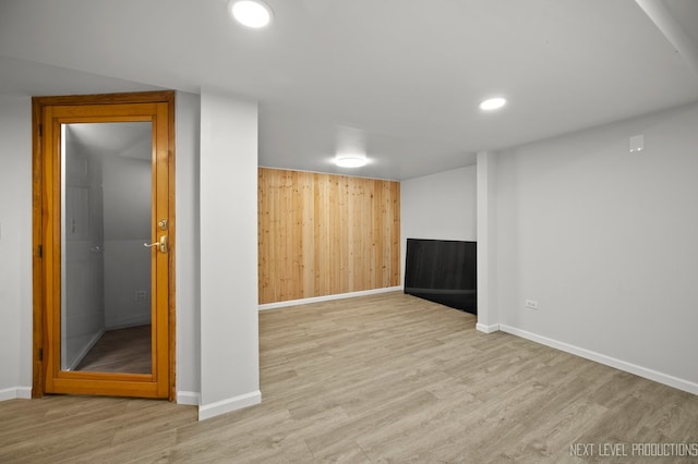 basement with wood walls and light wood-type flooring